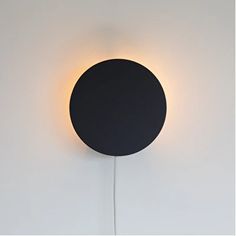 a black round light fixture on a white wall