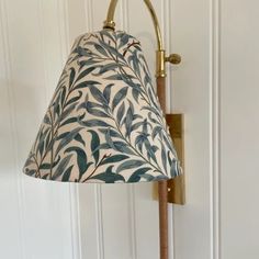 a lamp that is sitting on a wall next to a white door with a green leaf print shade