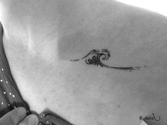 a woman's back with a wave tattoo on her left side ribcage