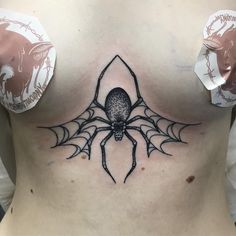 a woman's chest with a spider tattoo on the top and bottom part of her stomach