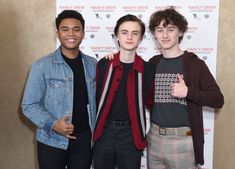 three young men standing next to each other in front of a sign with the name macy's on it