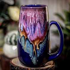 a purple and blue coffee mug sitting on top of a tree stump