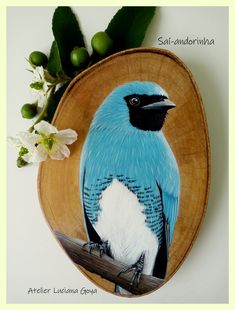 a blue and white bird sitting on top of a wooden plate next to some flowers