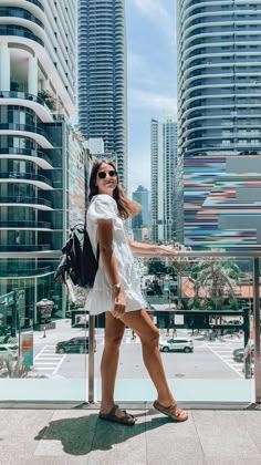 a woman standing in front of some tall buildings