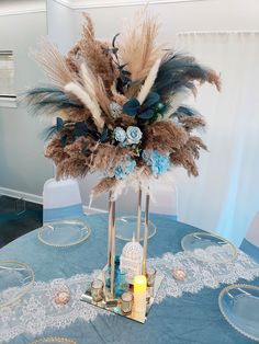 the centerpiece is decorated with feathers, flowers and candles on a blue table cloth