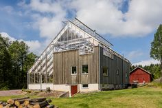 a house made out of wood and glass in the middle of a field next to a red barn