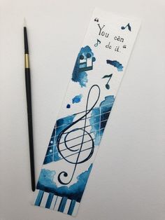 a bookmark with music notes on it next to a pencil and watercolor paint