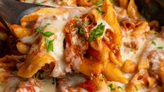 a close up of a plate of pasta with meat and cheese on it, being held by a wooden spoon