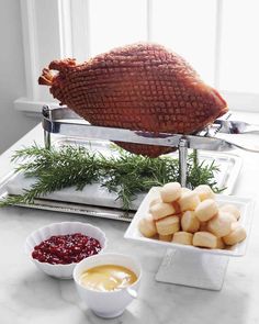 a turkey sitting on top of a counter next to potatoes and cranberry sauce