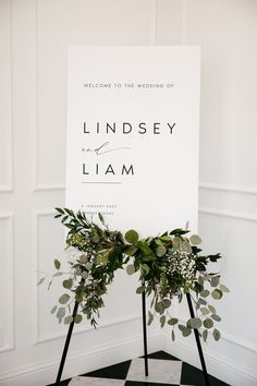 a sign with greenery on it sitting next to a black and white checkered floor