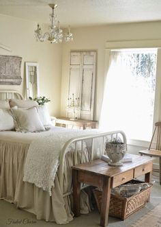 a white bed sitting next to a window in a room with a chandelier