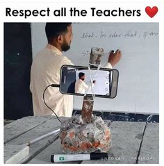 a man is taking a photo with his cell phone while standing in front of a rock