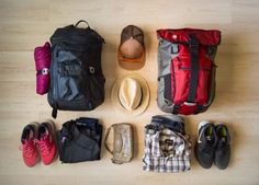 several pairs of shoes, hats, and backpacks laid out on a wooden floor