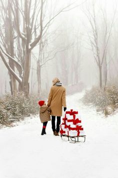 a man and child are walking in the snow with presents on a sleigh