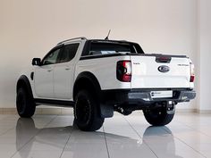 a white pick up truck parked in a room with tile flooring and large windows