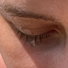 a close up of a person's eye with long eyelashes and water drops on it