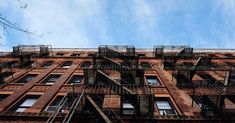 an old brick building with fire escapes and ladders on the top floor, against a blue sky