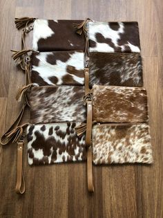 four different cowhides are laid out on the floor with leather tassels