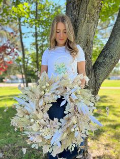 a woman standing next to a tree holding a wreath