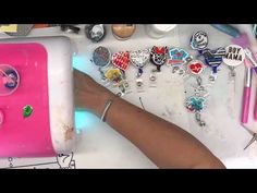 a person is holding onto a pink case with lots of charms on it and various other items