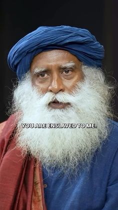 an old man with a long white beard and blue turban is looking at the camera