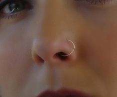 a woman's nose is shown with an ear piercing in the shape of a circle