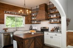 a kitchen with white cabinets and wooden shelves on the wall, an island in the middle