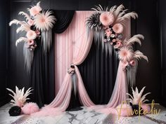 a black and pink wedding backdrop with flowers, feathers and tassels on it