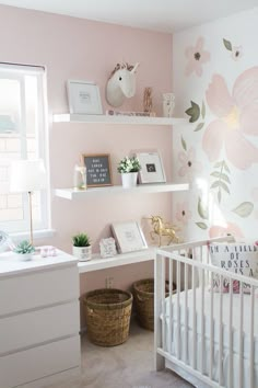 a baby's room decorated in pink and white with flowers painted on the wall