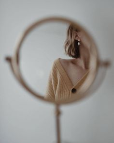 a woman looking through a magnifying glass at her reflection in the mirror,