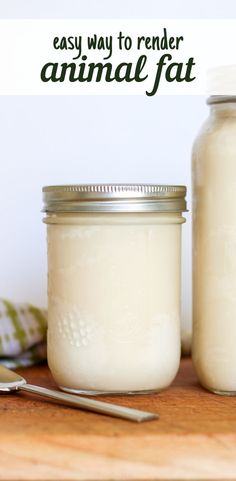 two jars filled with white liquid sitting on top of a wooden table next to a spoon