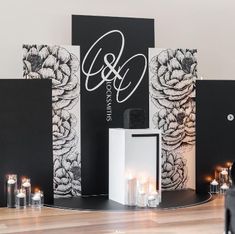 a stage set up for a wedding with black and white floral wallpaper, candles and monogrammed backdrop