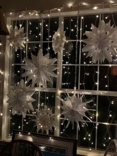 some white paper snowflakes hanging from a window