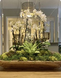 a wooden bowl filled with white flowers and greenery