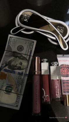 some lipstick, money and scissors on a table