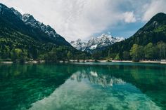 the water is crystal green and clear with mountains in the backgrouds behind it