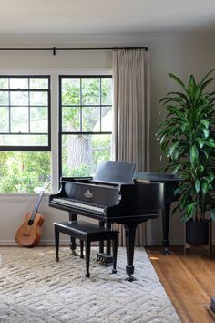 a living room filled with furniture and a piano in front of a window next to a potted plant