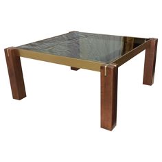 a glass and brass coffee table with metal legs