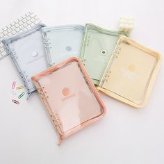 four different colored notebooks sitting next to each other on top of a white surface