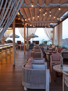 an outdoor seating area with lots of chairs and umbrellas on the roof overlooking the ocean