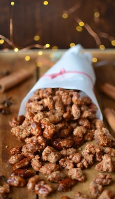 a pile of nuts sitting on top of a wooden cutting board next to cinnamon sticks