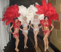 three women in red and white costumes standing next to each other with large feathers on their head