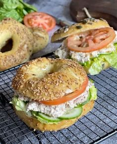 two bagel sandwiches on a cooling rack with tomatoes and lettuce