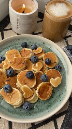 pancakes with blueberries and syrup on a plate next to a cup of coffee or tea