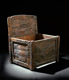 an old wooden box sitting on top of a black surface with the lid open and it's sides turned down