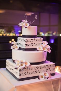 a wedding cake with music notes and flowers on it's tiered display table