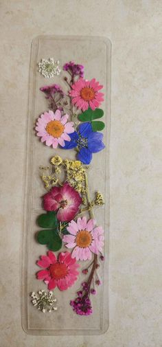 several different colored flowers in a clear plastic container on a counter top with silver and gold accents