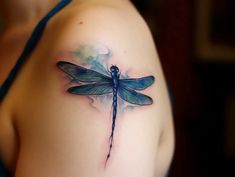 a blue dragonfly tattoo on the left shoulder