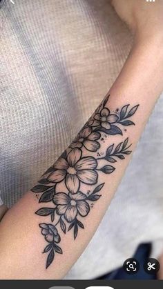 a woman's arm with flowers and leaves tattoo on the left side of her arm