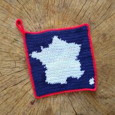 a crocheted pot holder with the shape of france on it sitting on top of a tree stump